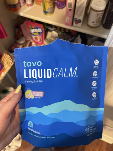 Hand holding a Tavo LiquidCalm liquid calm raspberry lemonade drink mix pack as part of an evening wind-down routine.
